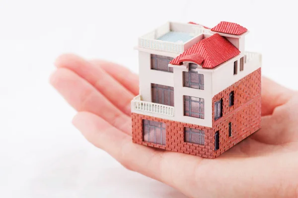 hand with model house on background, close up