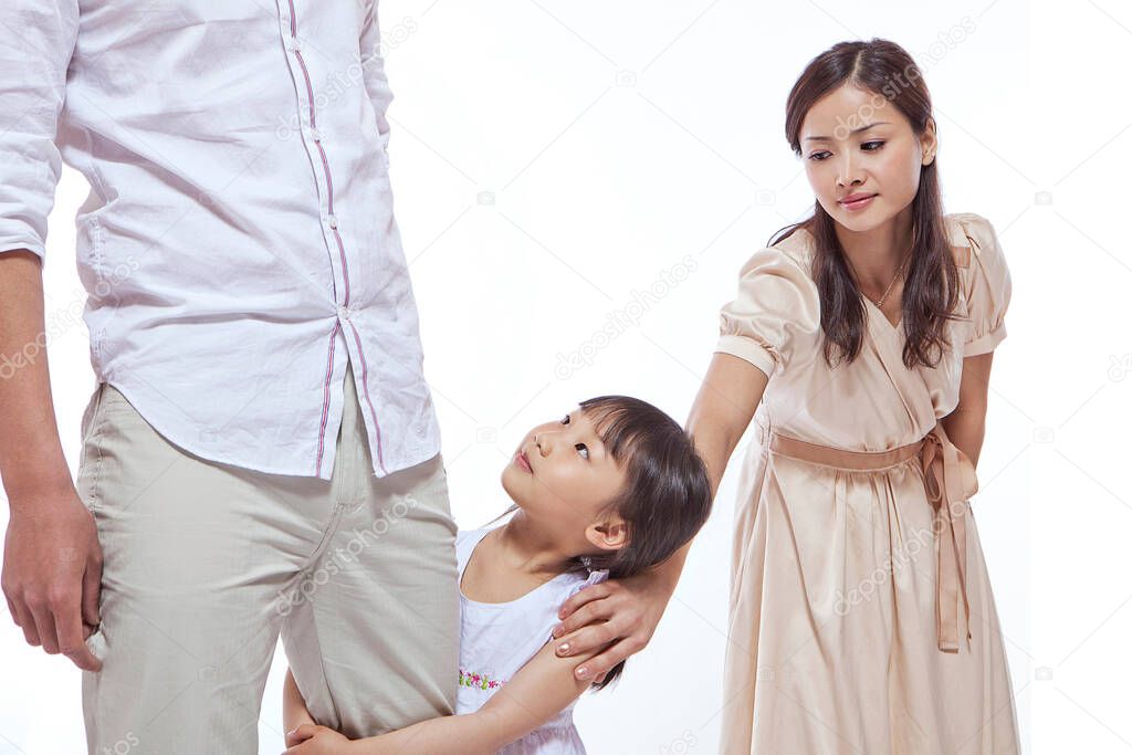 Girl clinching father's leg,mother pulling at daughter's shoulder