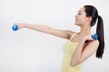 Mavi bir dambıl tutan genç bir bayan. 