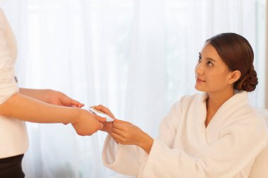 Beyaz cüppeli spa salonu müşterisi spa uzmanına hediye kartı veriyor. Vücut bakımı ve güzellik konsepti
