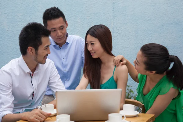 Company of people working at computer in cafe