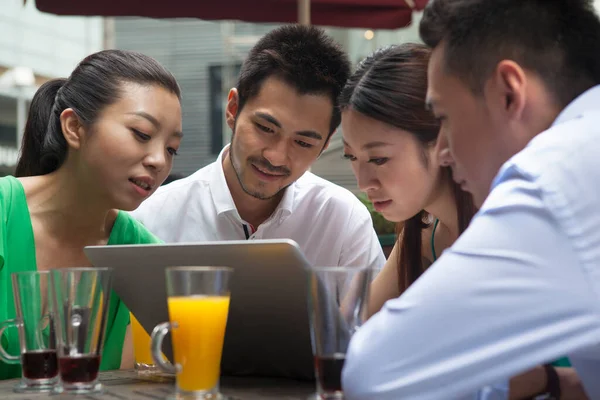 Company of people working at computer in cafe