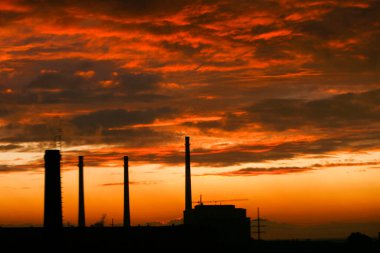 Arka planda fabrika bacası ve gün batımı