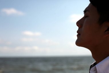 Deniz kenarında duran genç adam 