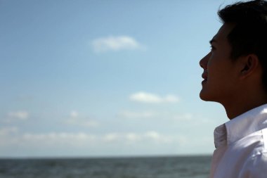 Deniz kenarında duran genç adam 