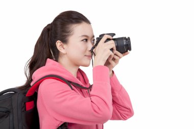 Sırt çantalı genç bir kadının fotoğrafı. Kameraya bakıyor.