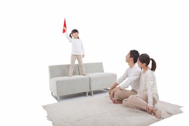 Kağıt uçak oynayan kızın portresi, halıda oturan ebeveynler.