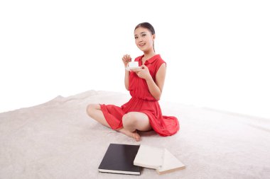 Genç bir kadın kahve içiyor, oturuyor.