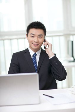 Masada oturan ve cep telefonu kullanan iş adamının portresi.