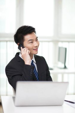 Masada oturan ve cep telefonu kullanan iş adamının portresi.