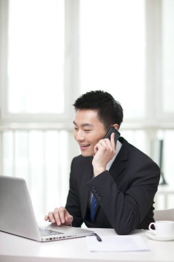 Masada oturan ve cep telefonu kullanan iş adamının portresi.