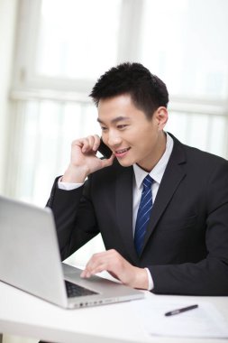 Masada oturan ve cep telefonu kullanan iş adamının portresi.