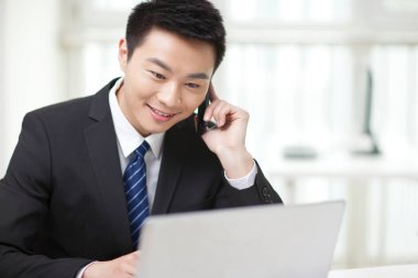 Masada oturan ve cep telefonu kullanan iş adamının portresi.