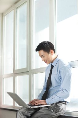 Koridorda dizüstü bilgisayar kullanan genç iş adamının portresi