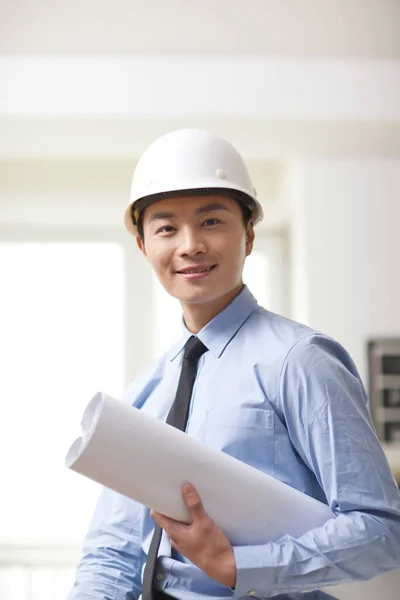 Retrato Del Joven Ingeniero Sosteniendo Plano Oficina —  Fotos de Stock