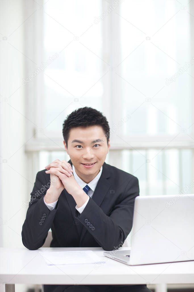 	Portrait of businessman sitting by laptop	