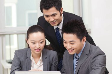 Bir grup iş adamı tartışıyorlar, bilgisayar üzerinde çalışıyorlar.