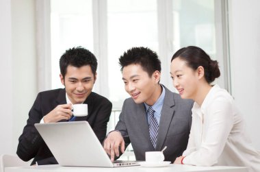 Bir grup iş adamı tartışıyorlar, bilgisayar üzerinde çalışıyorlar.