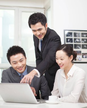 Bir grup iş adamı tartışıyorlar, bilgisayar üzerinde çalışıyorlar.