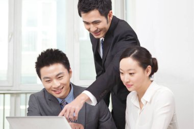 Bir grup iş adamı tartışıyorlar, bilgisayar üzerinde çalışıyorlar.