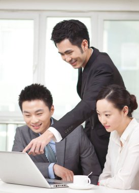 Bir grup iş adamı tartışıyorlar, bilgisayar üzerinde çalışıyorlar.