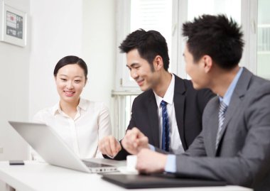 Bir grup iş adamı tartışıyorlar, bilgisayar üzerinde çalışıyorlar.