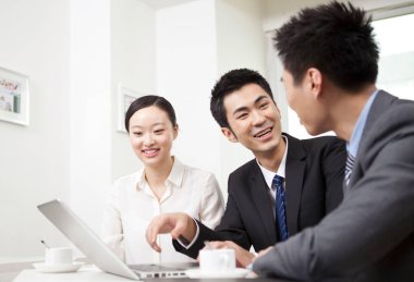 Bir grup iş adamı tartışıyorlar, bilgisayar üzerinde çalışıyorlar.