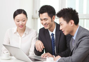 Bir grup iş adamı tartışıyorlar, bilgisayar üzerinde çalışıyorlar.