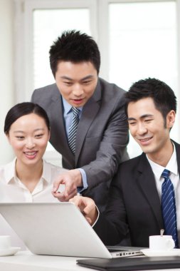 Bir grup iş adamı tartışıyorlar, bilgisayar üzerinde çalışıyorlar.