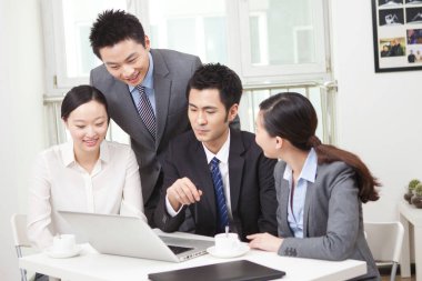 Bir grup iş adamı tartışıyorlar, bilgisayar üzerinde çalışıyorlar.