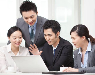 Bir grup iş adamı tartışıyorlar, bilgisayar üzerinde çalışıyorlar.