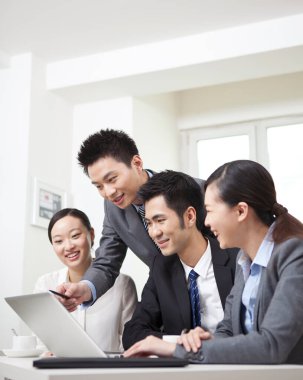 Bir grup iş adamı tartışıyorlar, bilgisayar üzerinde çalışıyorlar.