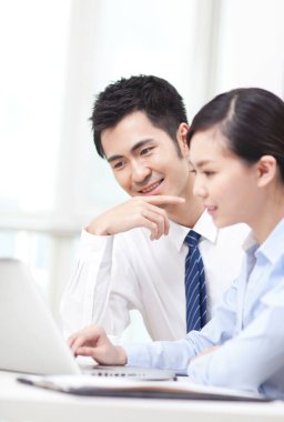 İş adamı ve iş kadını tartışıyorlar, bilgisayar üzerinde çalışıyorlar.