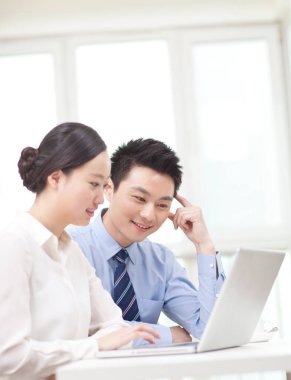 İş adamı ve iş kadını tartışıyorlar, bilgisayar üzerinde çalışıyorlar.