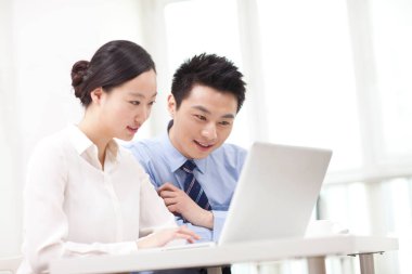 İş adamı ve iş kadını tartışıyorlar, bilgisayar üzerinde çalışıyorlar.