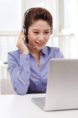 Dizüstü bilgisayar kullanan kulaklıklı bir iş kadını.