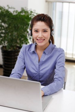 Dizüstü bilgisayar kullanan kulaklıklı bir iş kadını.