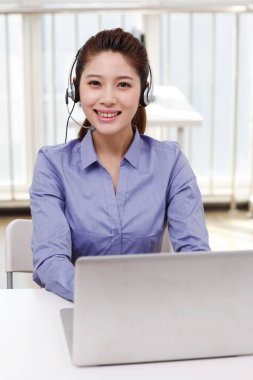 Dizüstü bilgisayar kullanan kulaklıklı bir iş kadını.