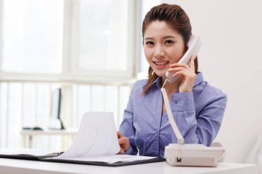 İş kadını akıllı telefon kullanıyor, kitap okuyor.