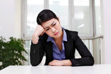 İş kadını masanın yanında oturuyor.