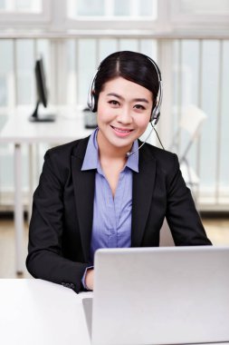 Bilgisayar kullanan kulaklıklı bir iş kadını.