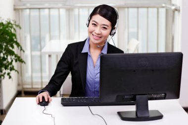 Bilgisayar kullanan kulaklıklı bir iş kadını.