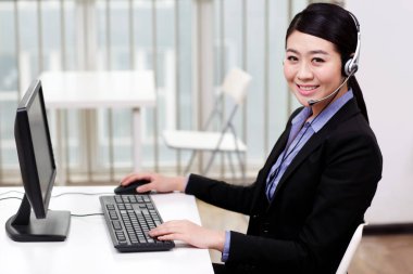 Bilgisayar kullanan kulaklıklı bir iş kadını.