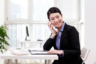 İş kadını cep telefonu kullanıyor, portföy okuyor.