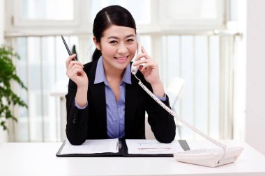 İş kadını cep telefonu kullanıyor, portföy okuyor.