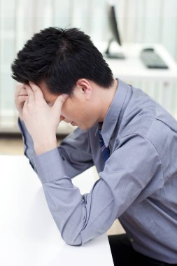 Bir adam masasında çalışırken stresli görünür.