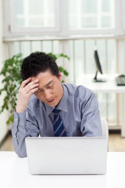 Ofiste dizüstü bilgisayar kullanan bir iş adamının yakın çekimi.