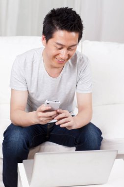 Kanepede dizüstü bilgisayar kullanan neşeli bir iş adamı.