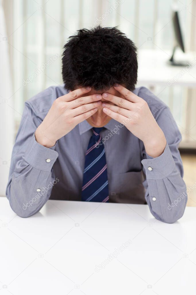 	A man looks stressed as he works at his desk	