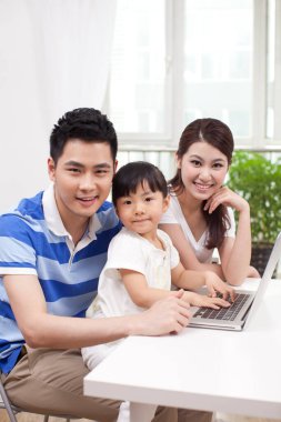 Dizüstü bilgisayar kullanan üç kişilik aile